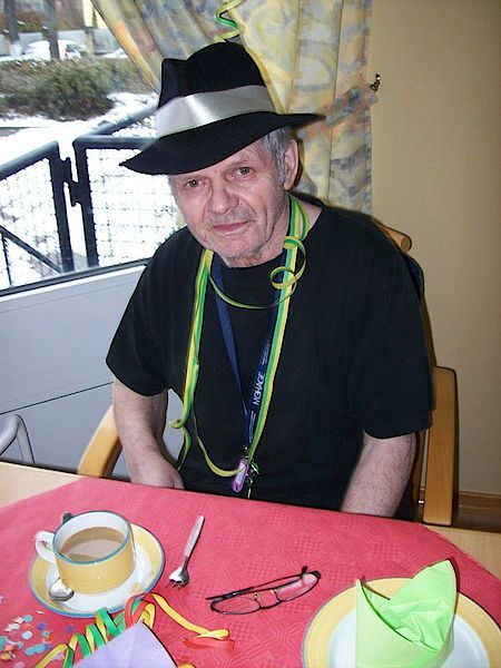 Ein Mann mit Hut sitzt mit einer Tasse Kaffee an einem Tisch