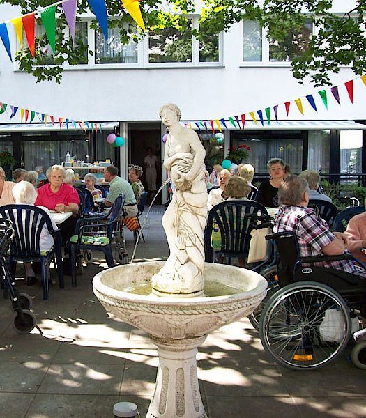 Eine Gruppe von Menschen sitzt an Tischen vor einem Brunnen
