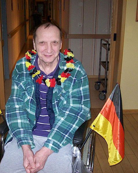 Ein Mann in einem grün karierten Hemd sitzt im Rollstuhl