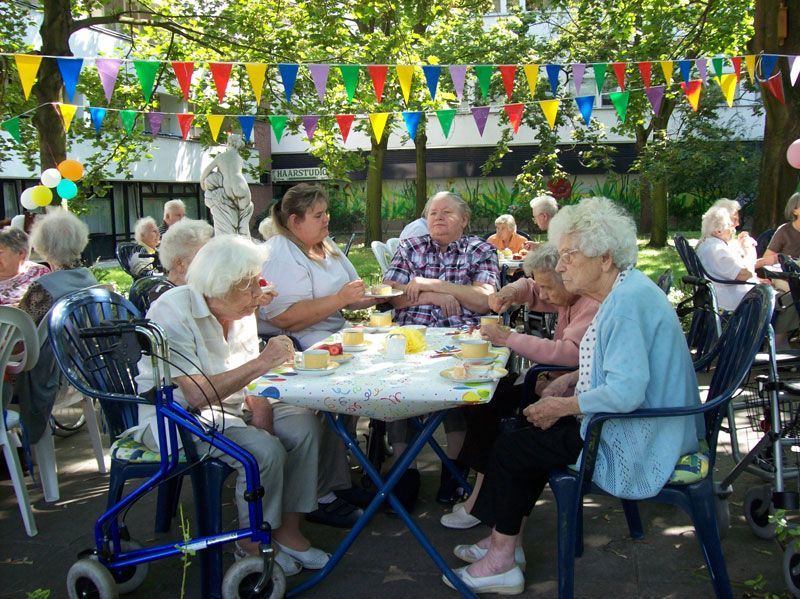 Eine Gruppe älterer Menschen sitzt an einem Tisch in einem Park