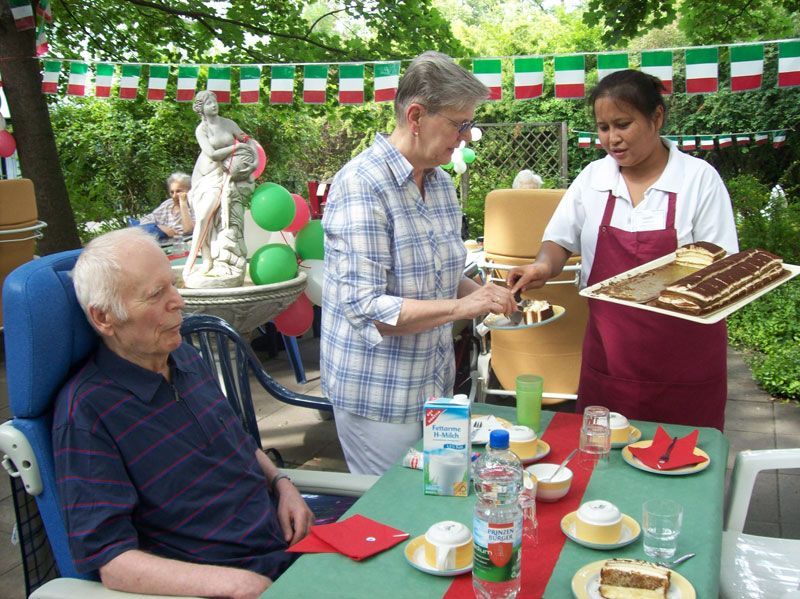 Eine Frau serviert einem älteren Mann einen Kuchen