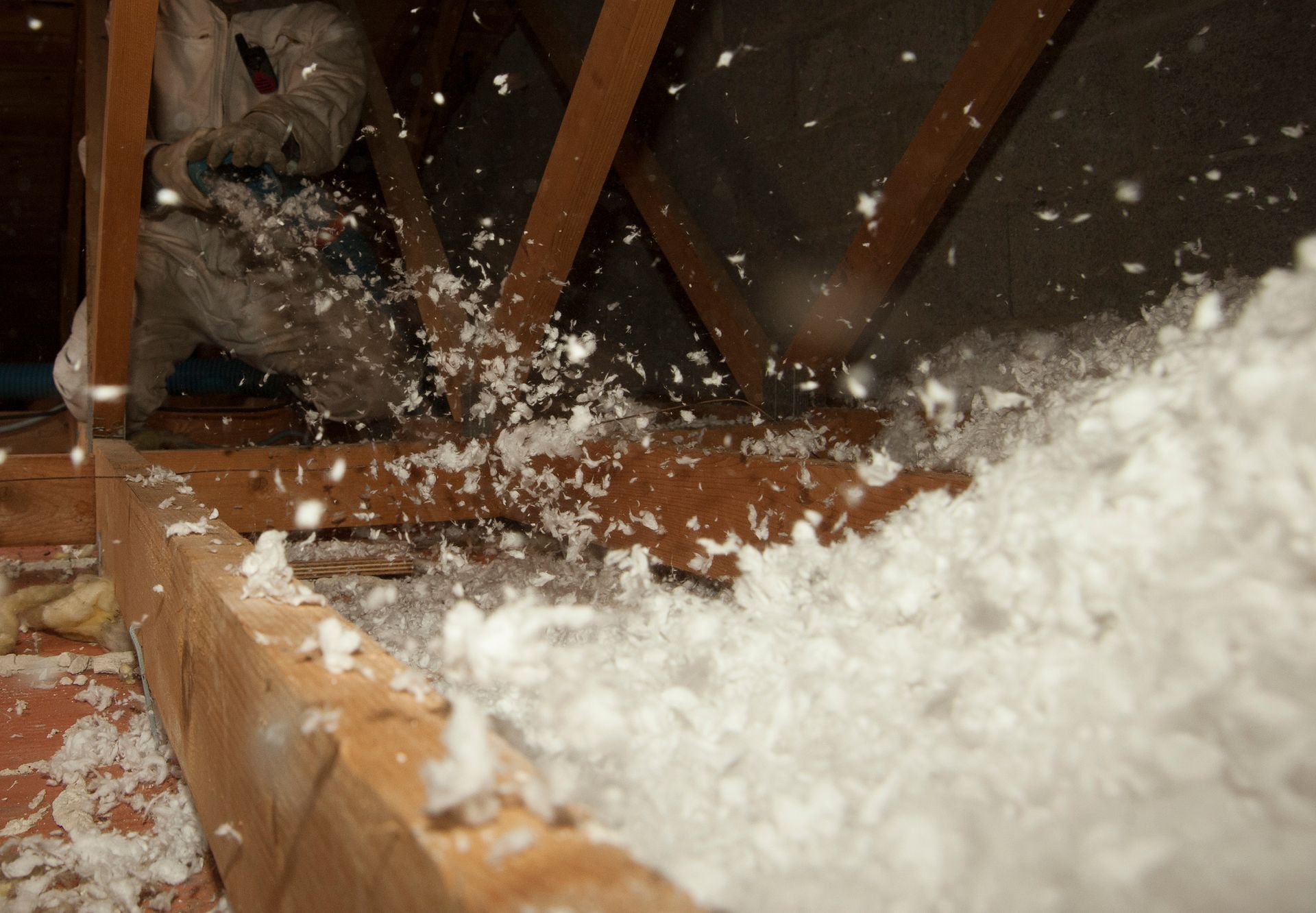 La neige s'infiltre dans un grenier en bois à travers les poutres apparentes du toit.