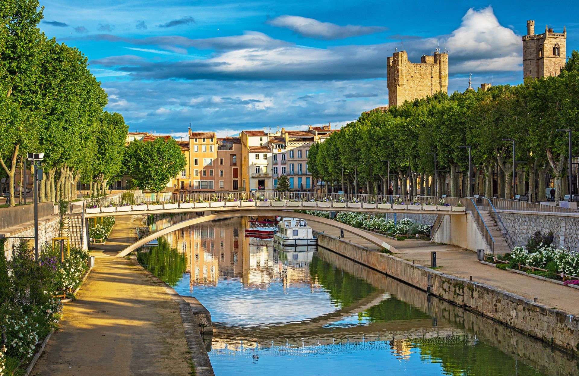 Canal bordé d'arbres près d'une ville historique et d'un château sous un ciel bleu