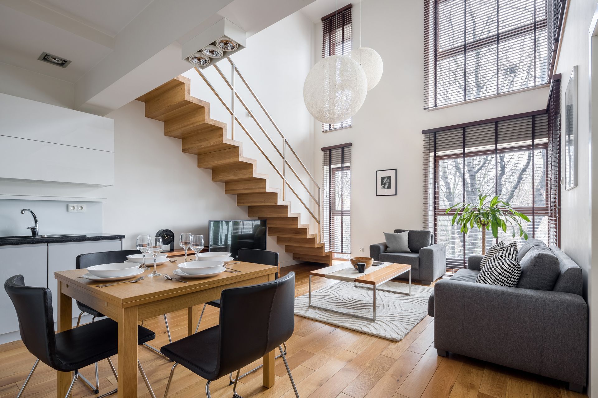 Maison blanche moderne avec un toit sombre et une pelouse verte sous un ciel bleu clair