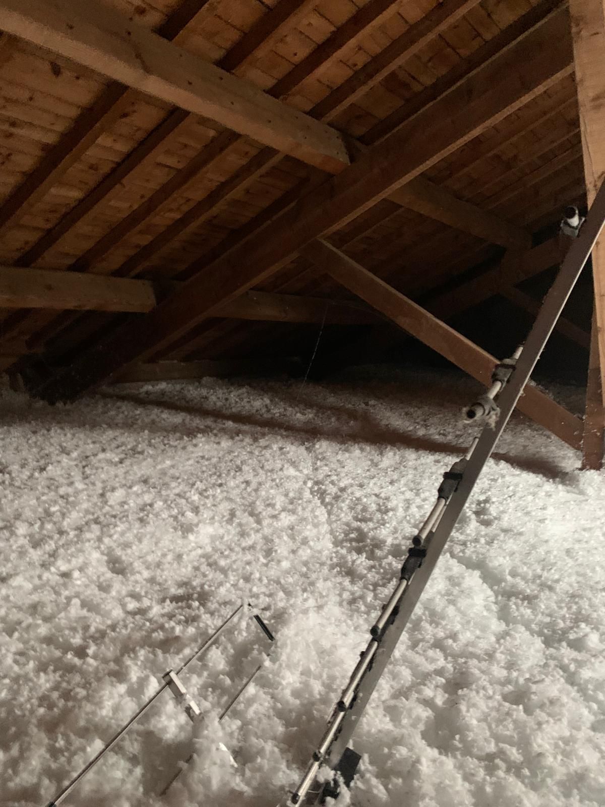 Gros plan sur une ossature murale isolée avec des montants en bois et des profilés métalliques sur une surface beige