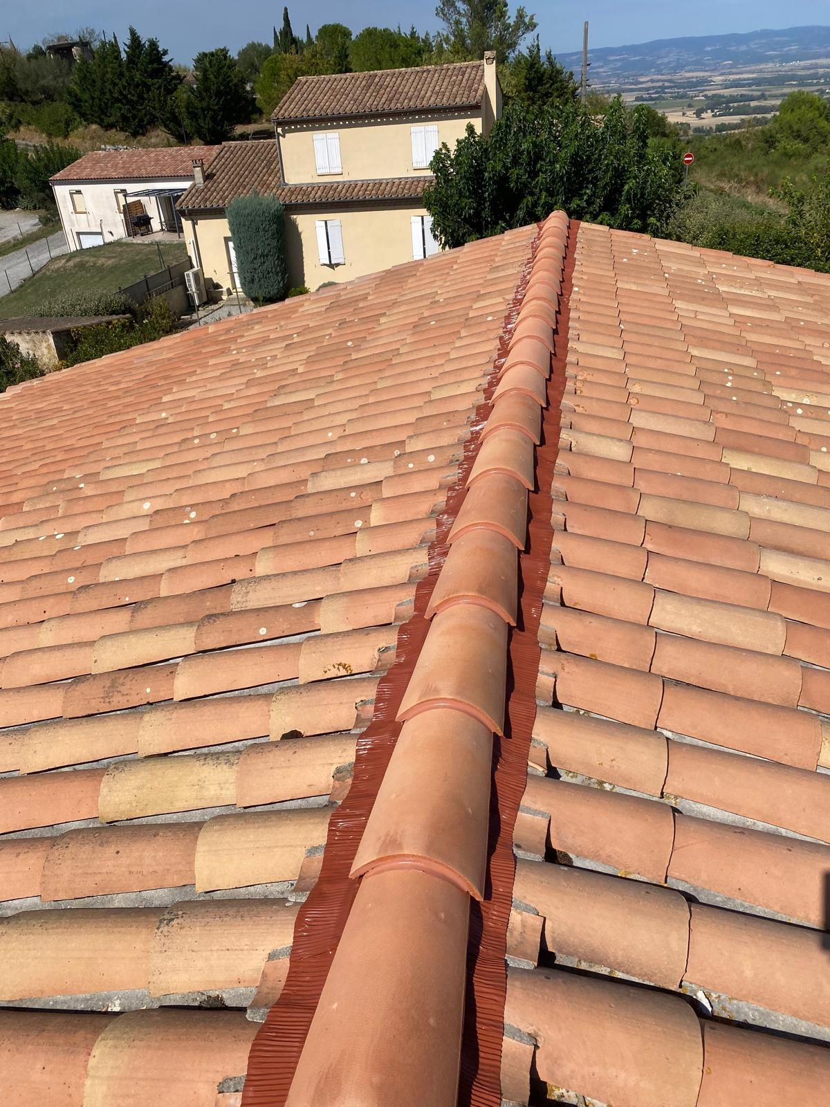 Toit de maison moderne en bardeaux gris foncé et murs de briques rouges sur fond de ciel bleu