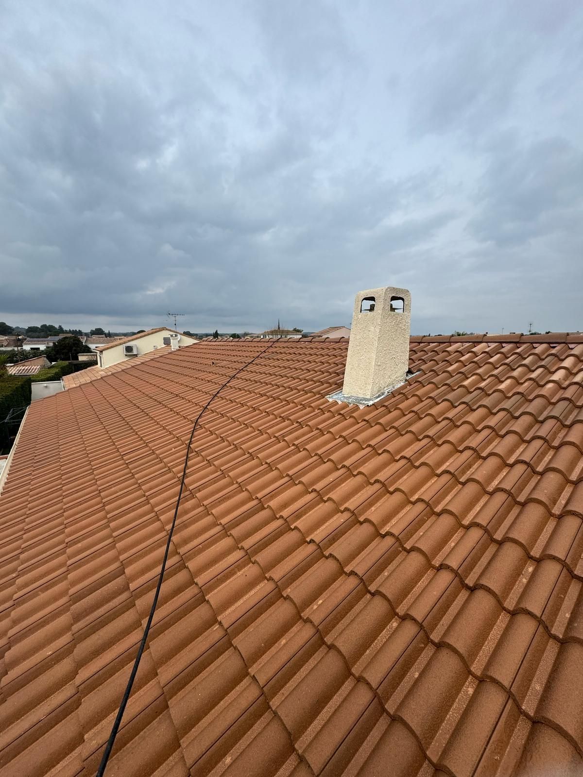 Toits de maisons modernes en tuiles gris foncé et murs en briques orange sous un ciel bleu