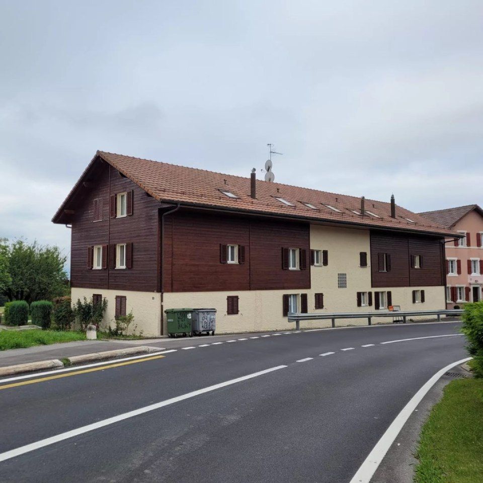 Une maison avec un toit rouge est à côté d'une route