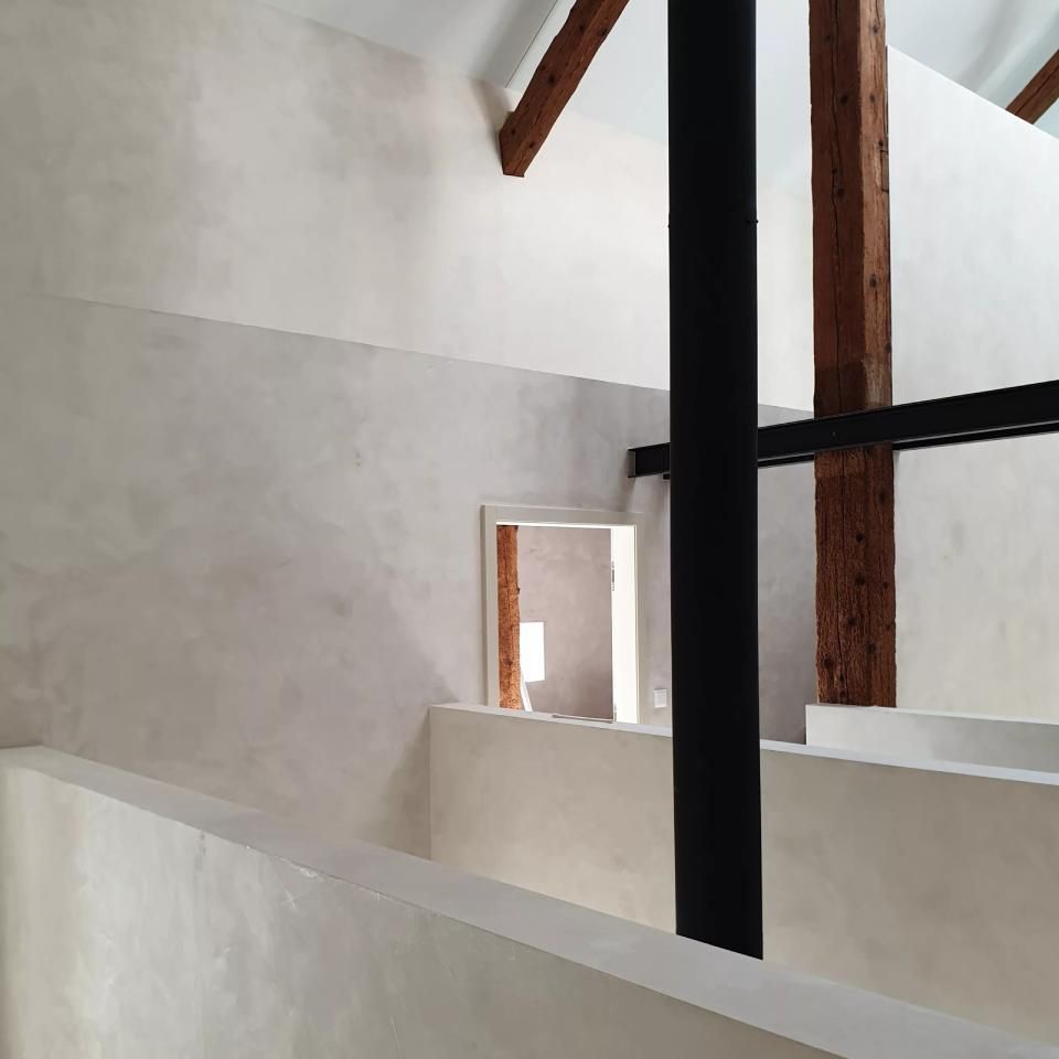 Un escalier dans un immeuble avec une rampe noire et des poutres en bois