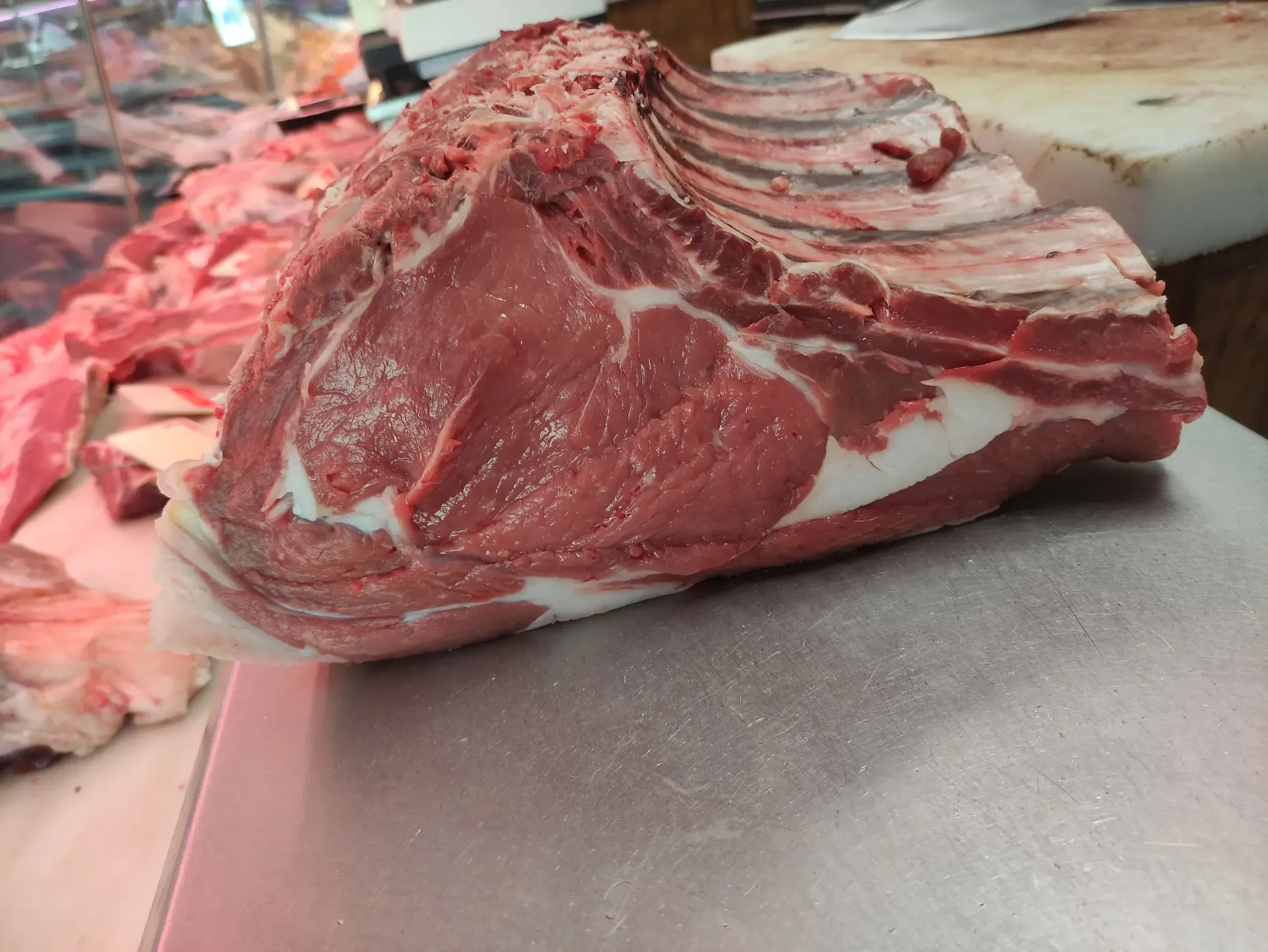 Un gran trozo de carne cruda reposa sobre una tabla de cortar.