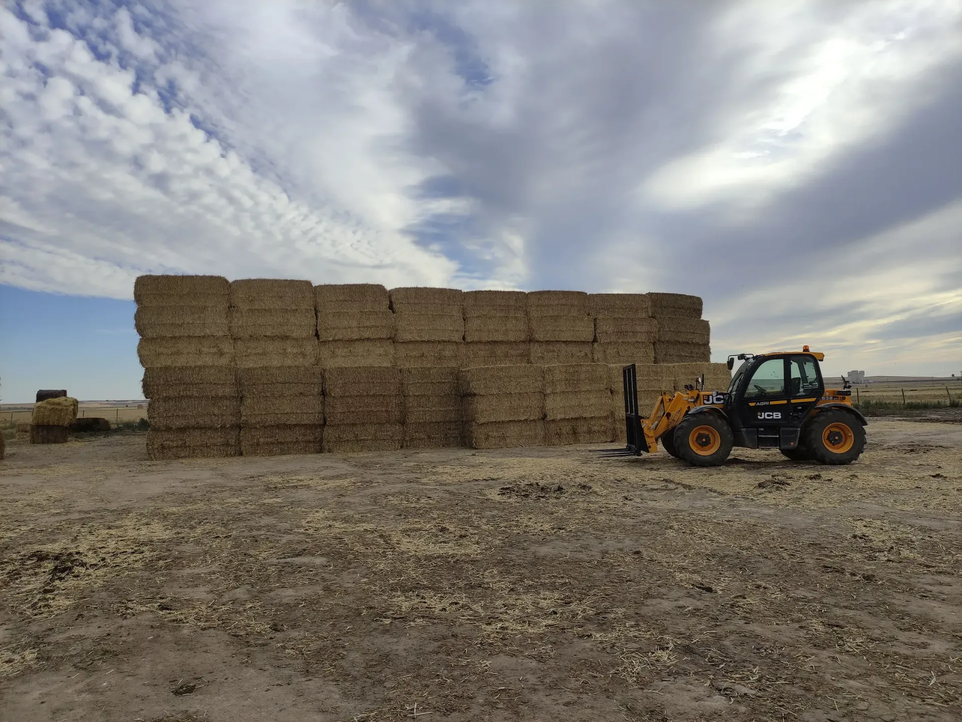 Un tractor transporta fardos de heno en un campo.