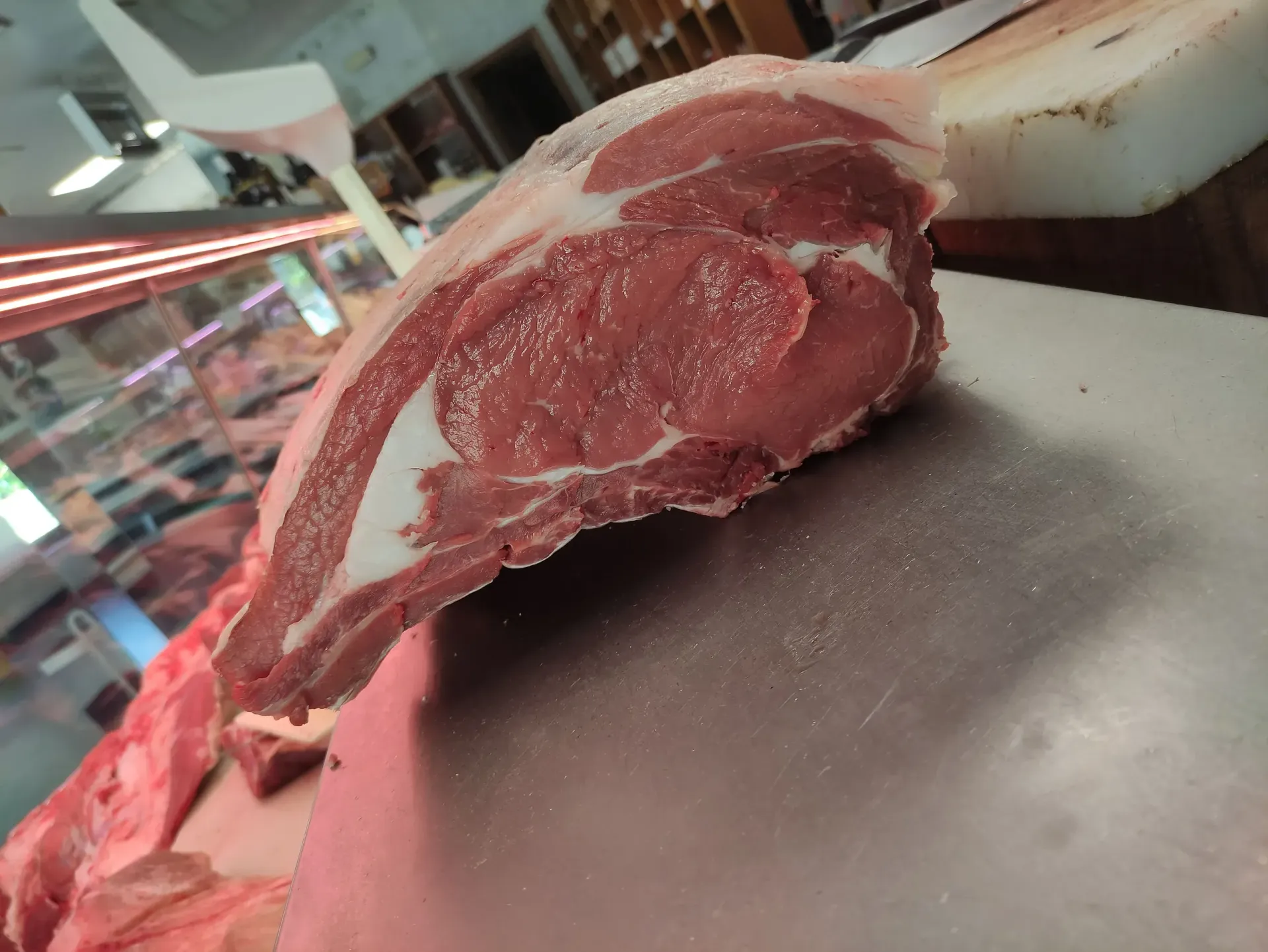 Un trozo de carne cruda está sobre una tabla de cortar.