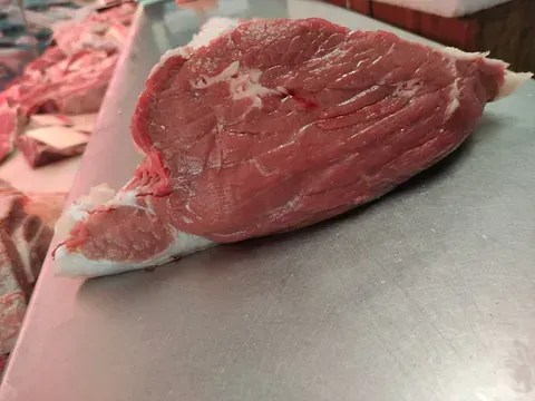 Un trozo de carne cruda está sobre una tabla de cortar.