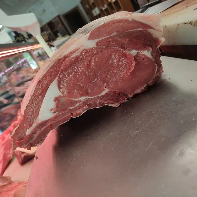 Un gran trozo de carne cruda reposa sobre una tabla de cortar.