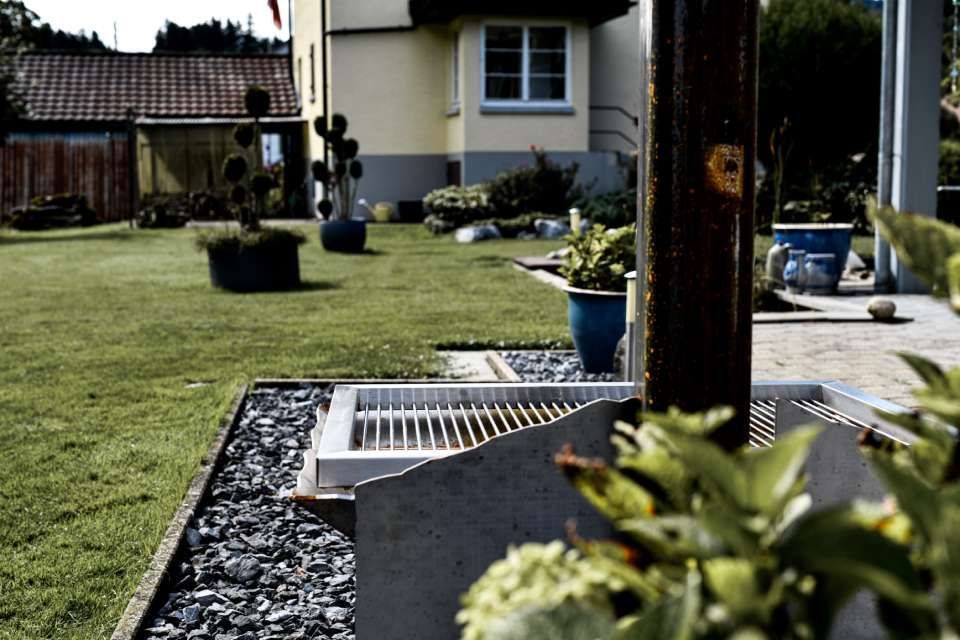 Hinterhof mit Design Grill, Rasen, Pflanzen und einem zweistöckigen Haus.