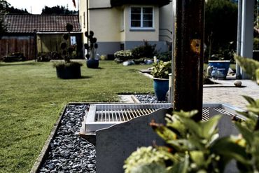 Hinterhof mit Design Grill, Rasen, Pflanzen und einem zweistöckigen Haus.