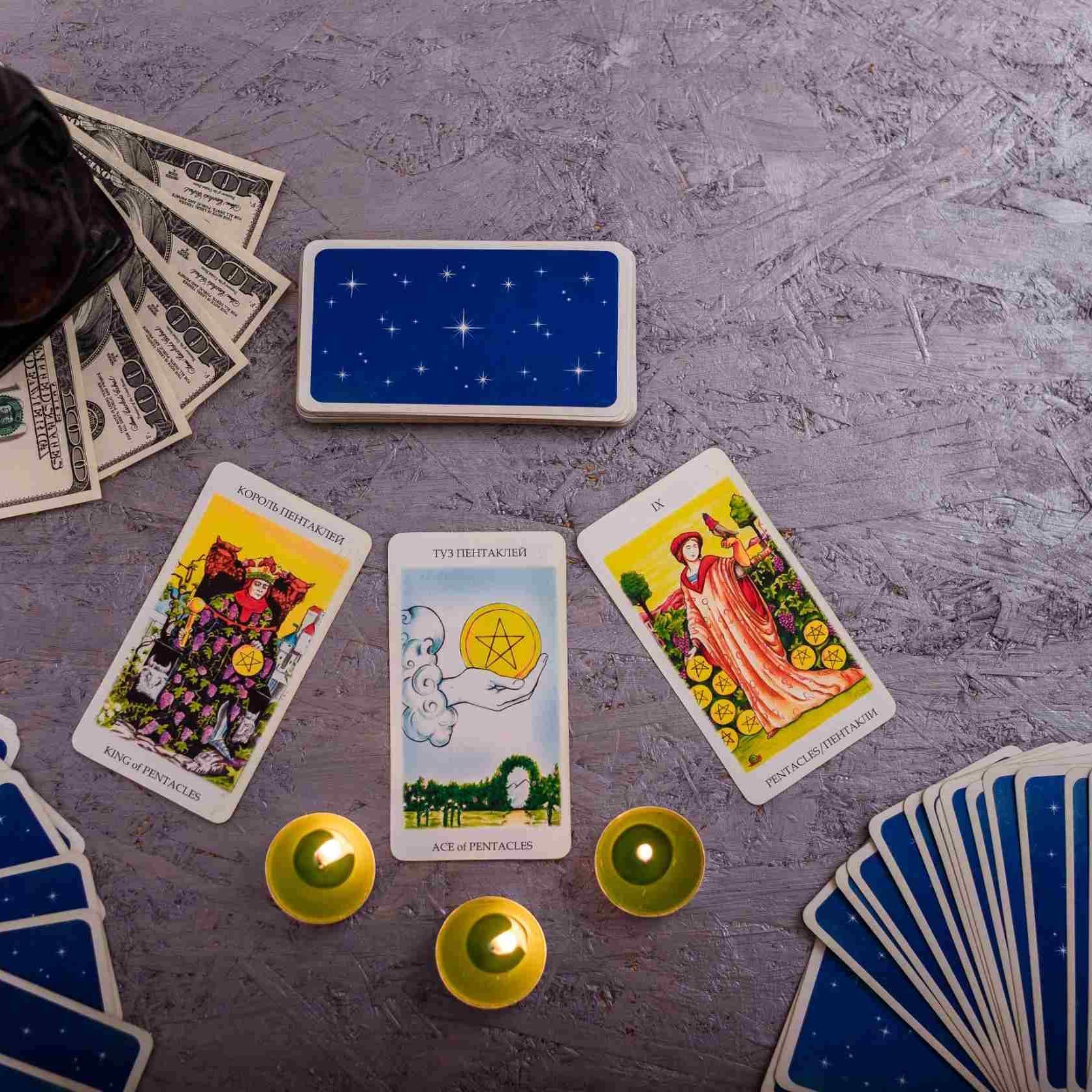 Una mesa cubierta con cartas de tarot, velas y dinero.