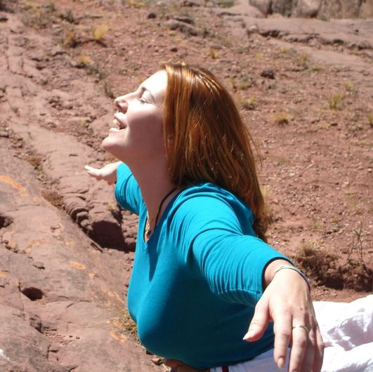 Una mujer con una camisa azul y los brazos extendidos.