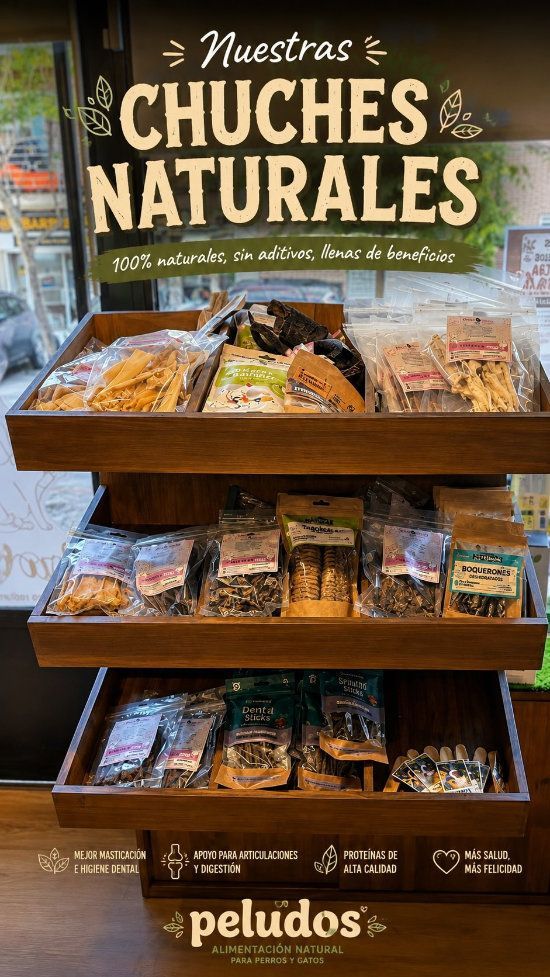 Exhibición de madera de bocadillos naturales variados en una tienda, etiquetados como “Nuestros Chuches Naturales” y “peludos”.
