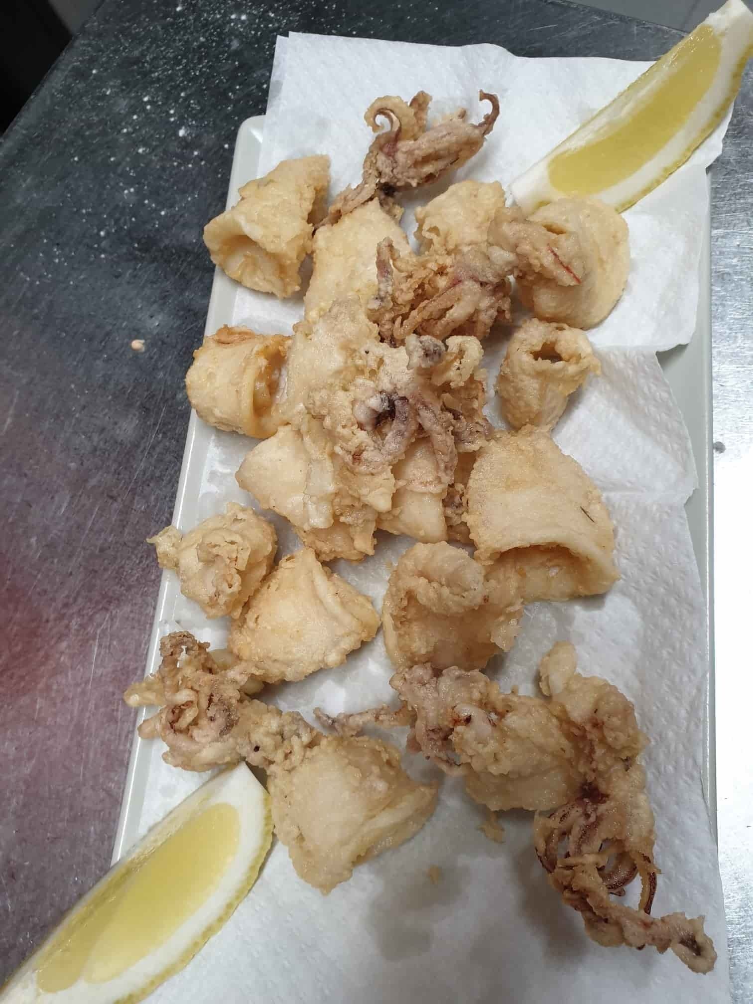 Un plato de calamares fritos con rodajas de limón en una servilleta.