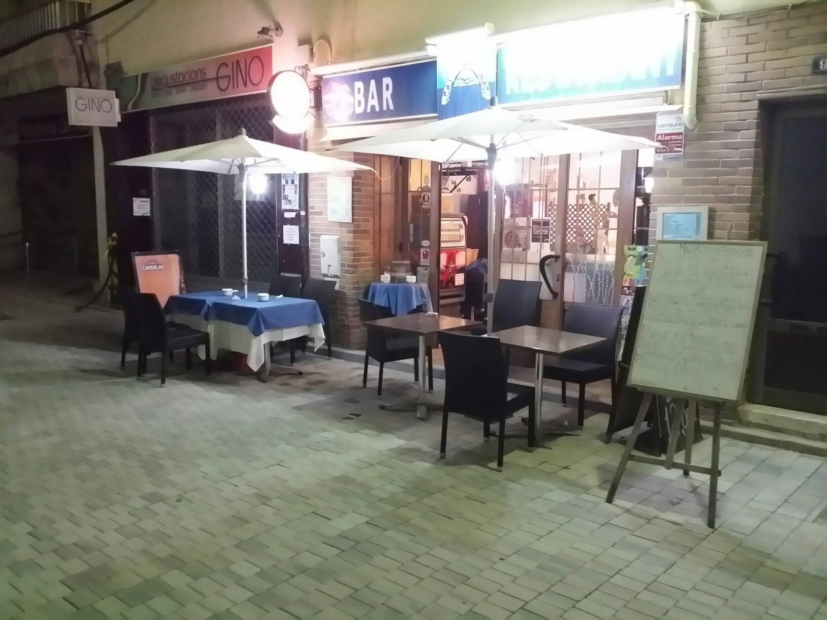 Un restaurante con mesas y sillas al aire libre por la noche.