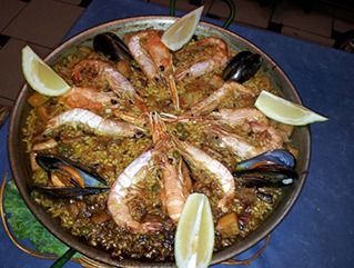 Una paella con camarones, mejillones y rodajas de limón