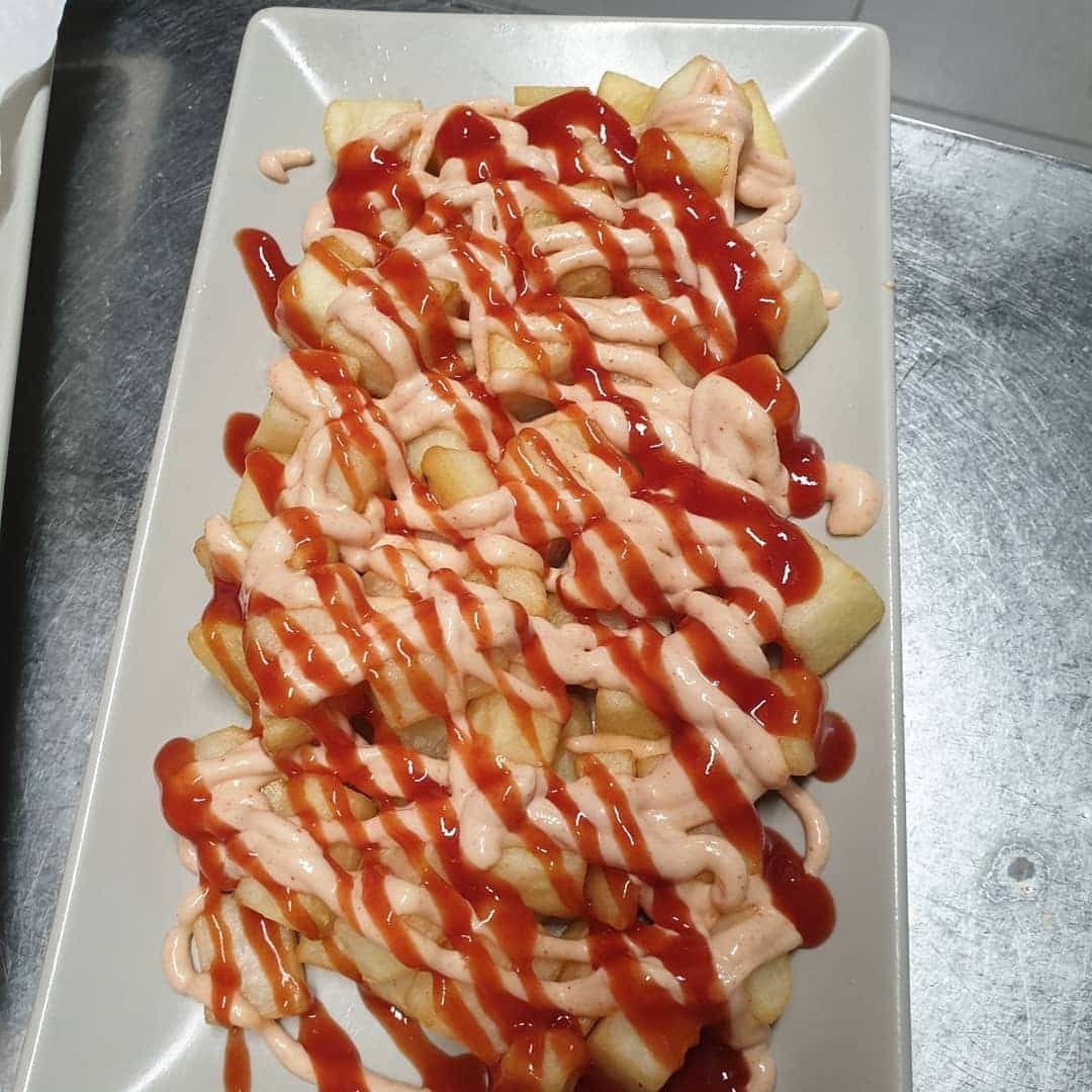 Un plato blanco cubierto con papas fritas y ketchup