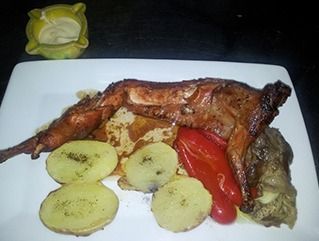 Un plato blanco cubierto con carne, patatas y pimientos.