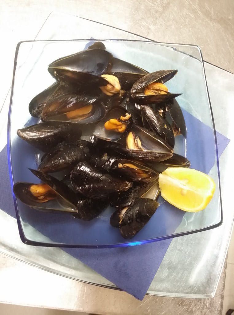 Un plato de mejillones con una rodaja de limón