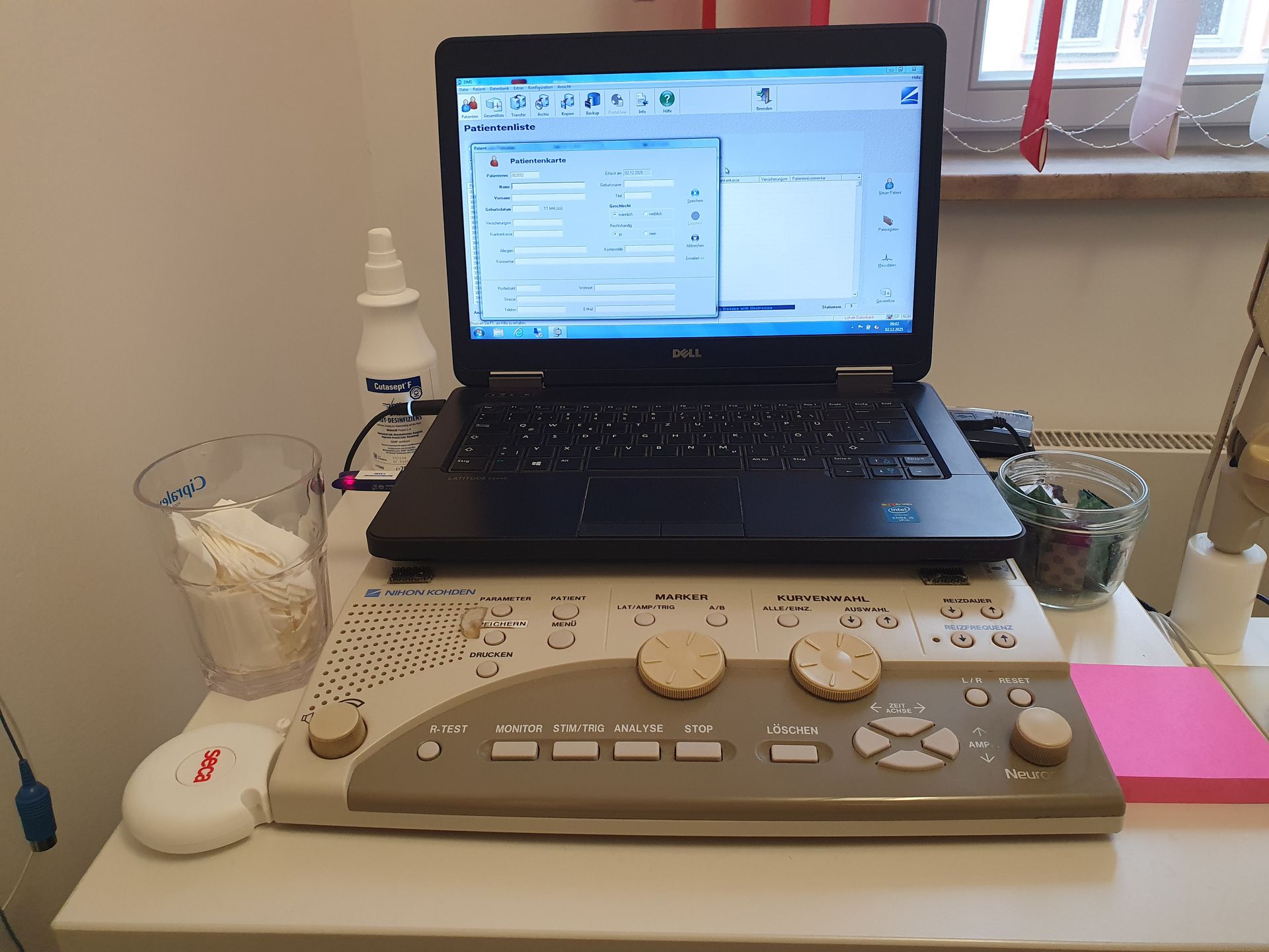 Audiometer mit zwei Drehreglern und mehreren Tasten auf einem Tisch vor einem geöffneten Laptop