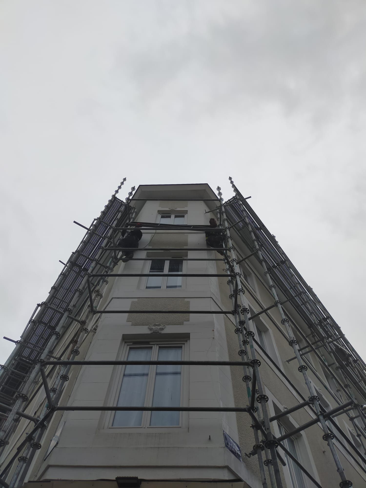 Cadre de fenêtre blanc avec poignée grise, vue sur les arbres à l'extérieur.