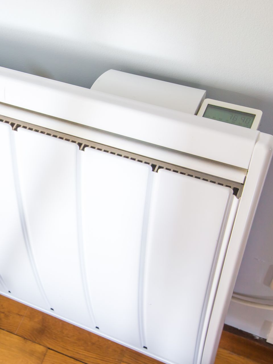 Radiateur électrique blanc fixé au mur, affichage digital visible.