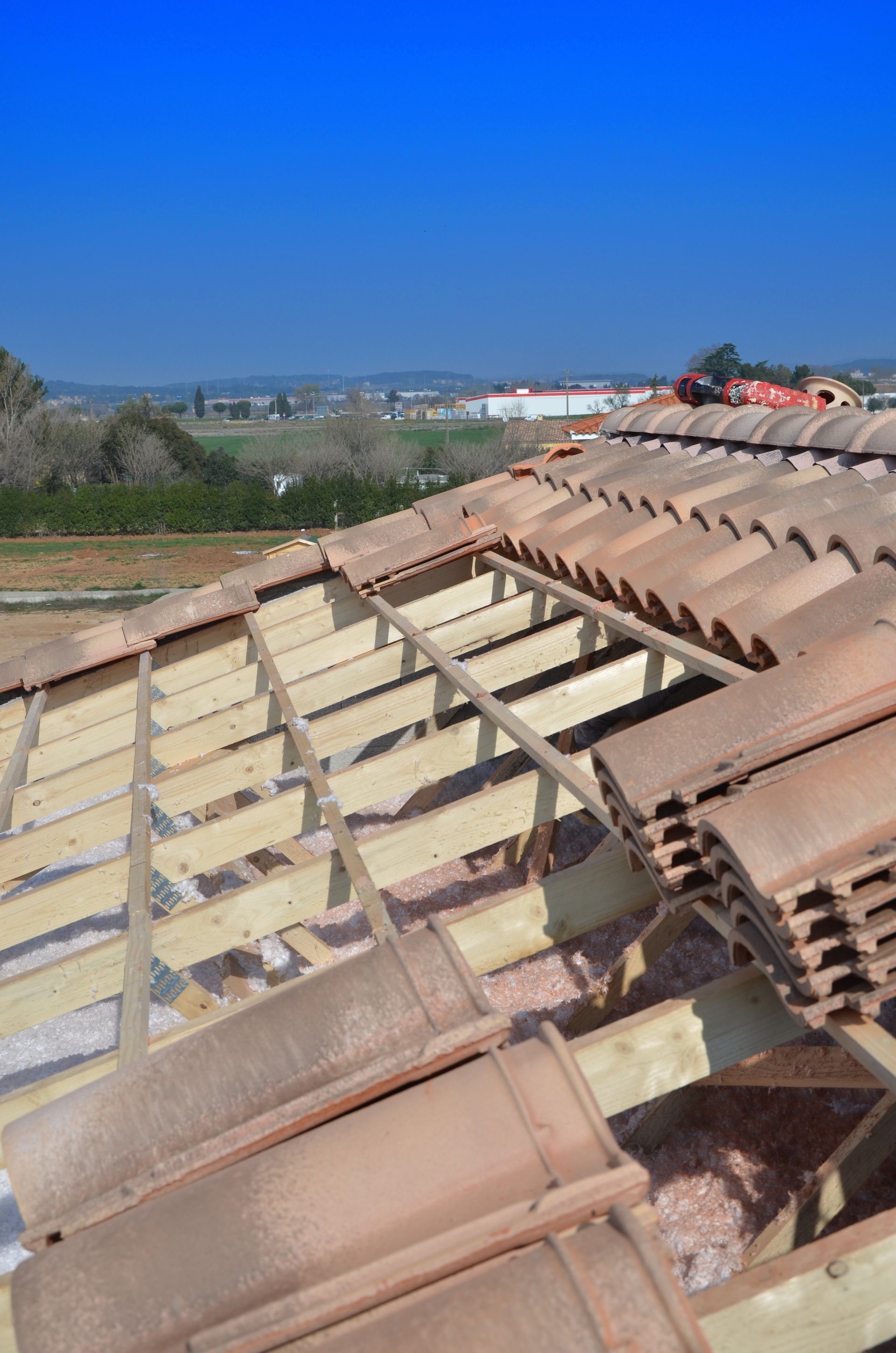 Pose de tuiles sur toiture en rénovation avec charpente apparente