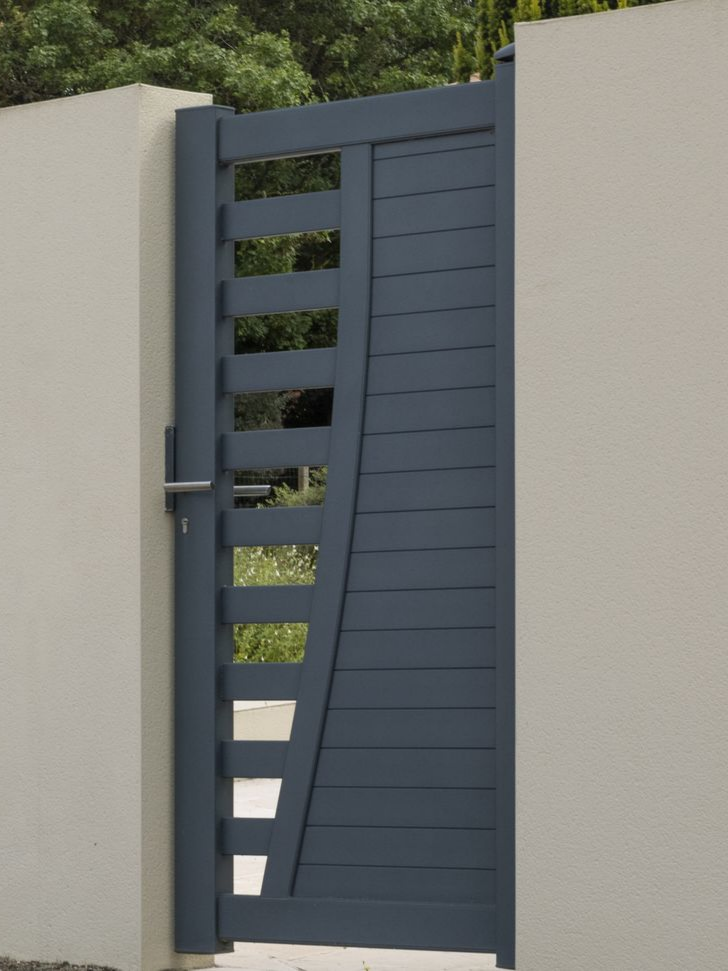 Portail en métal gris au design géométrique implanté dans un mur blanc.