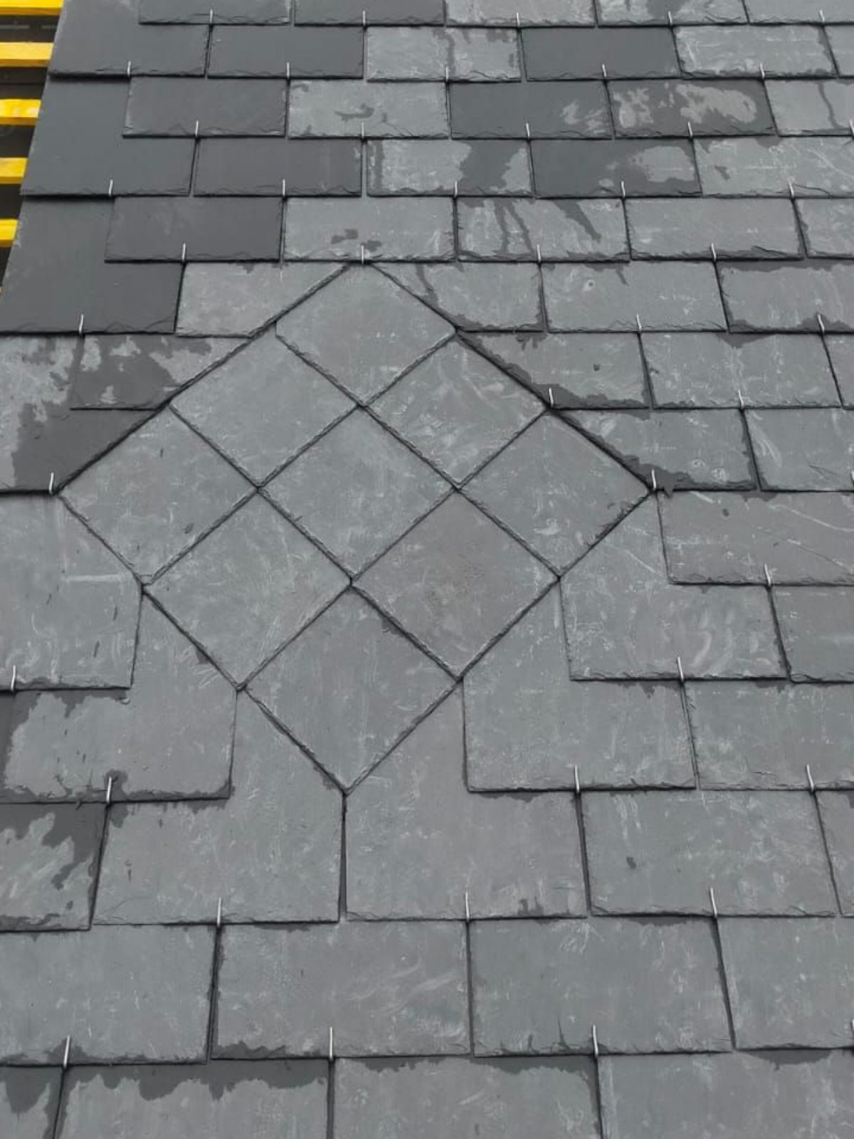 Couvreur en chemise et casquette vertes installant des tuiles en terre cuite rouge sur une maison.