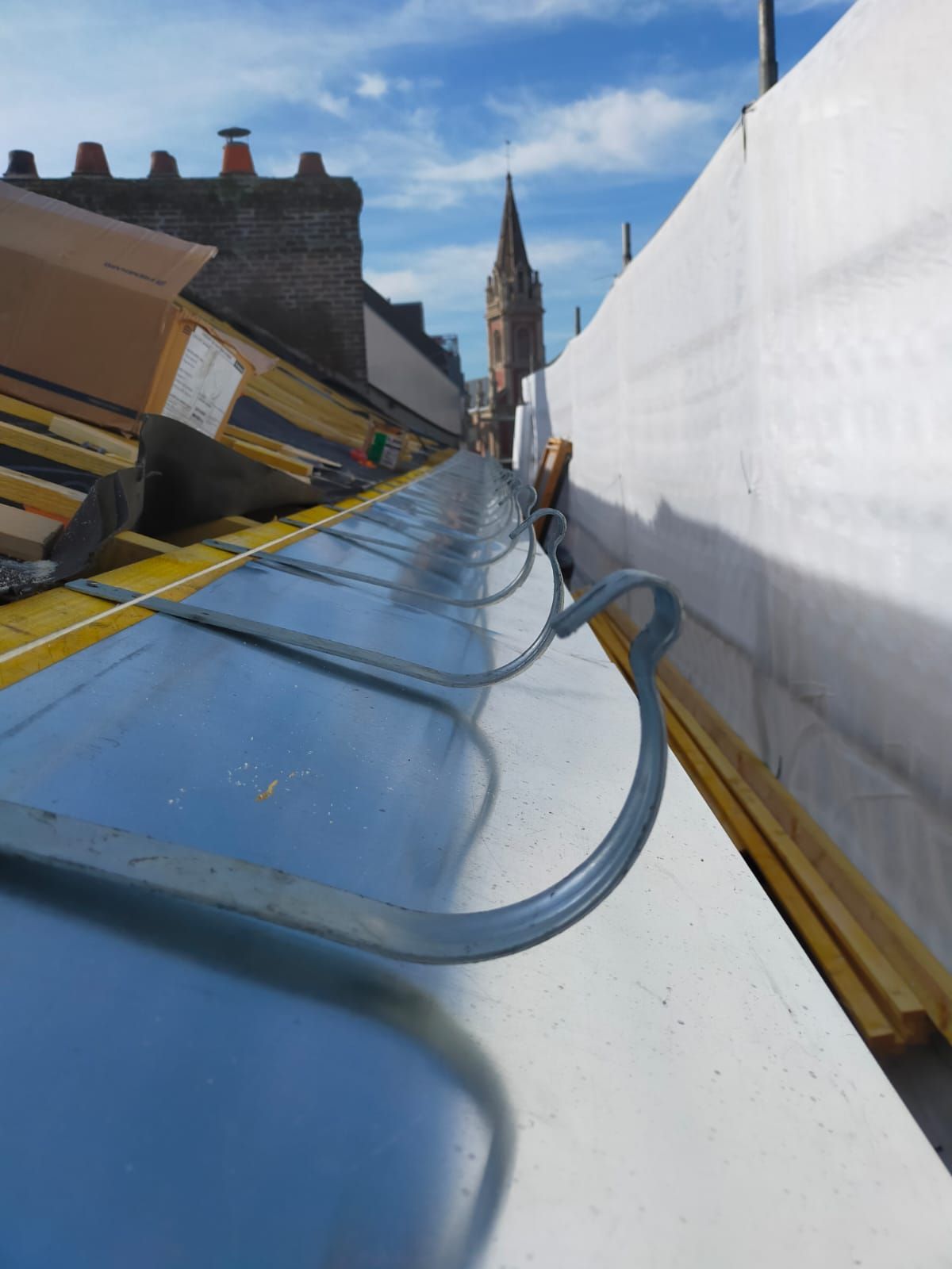 Solin de cheminée sur un toit en tuiles en terre cuite, avec une vue rapprochée du solin métallique contre la cheminée.