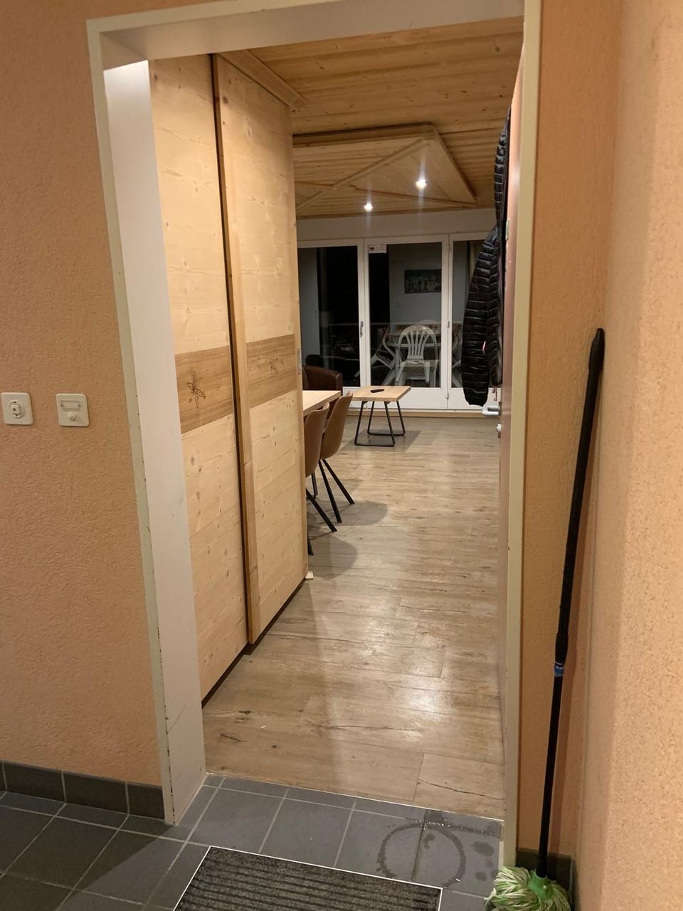 Une porte menant à un salon avec une vadrouille au sol.