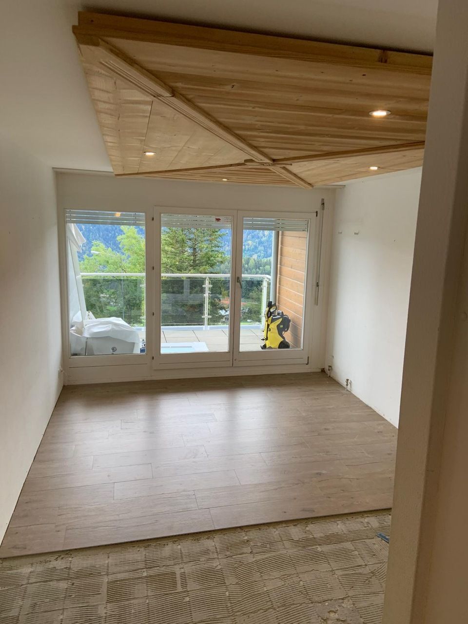 Un salon vide avec parquet et plafond en bois.