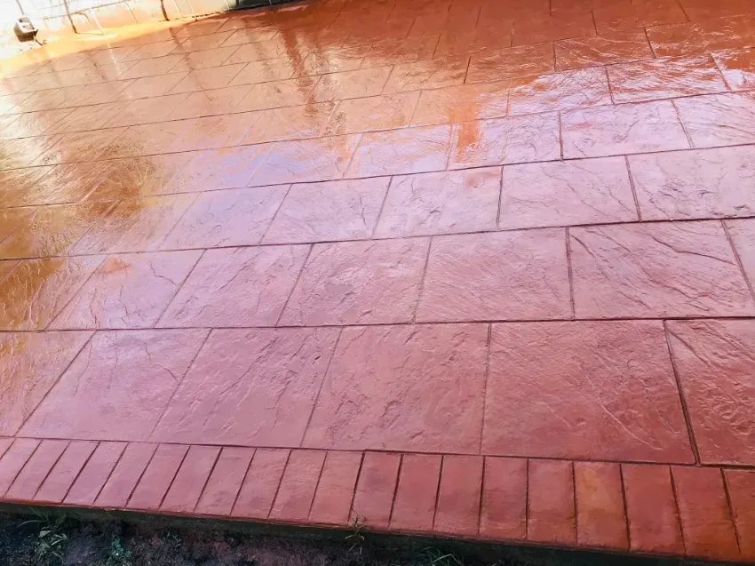 Suelo de patio con baldosas rojas y la luz del sol reflejándose en la superficie.