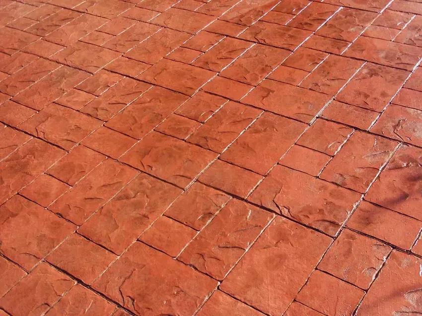 Pavimento de baldosas de color naranja rojizo agrietadas con juntas blancas.