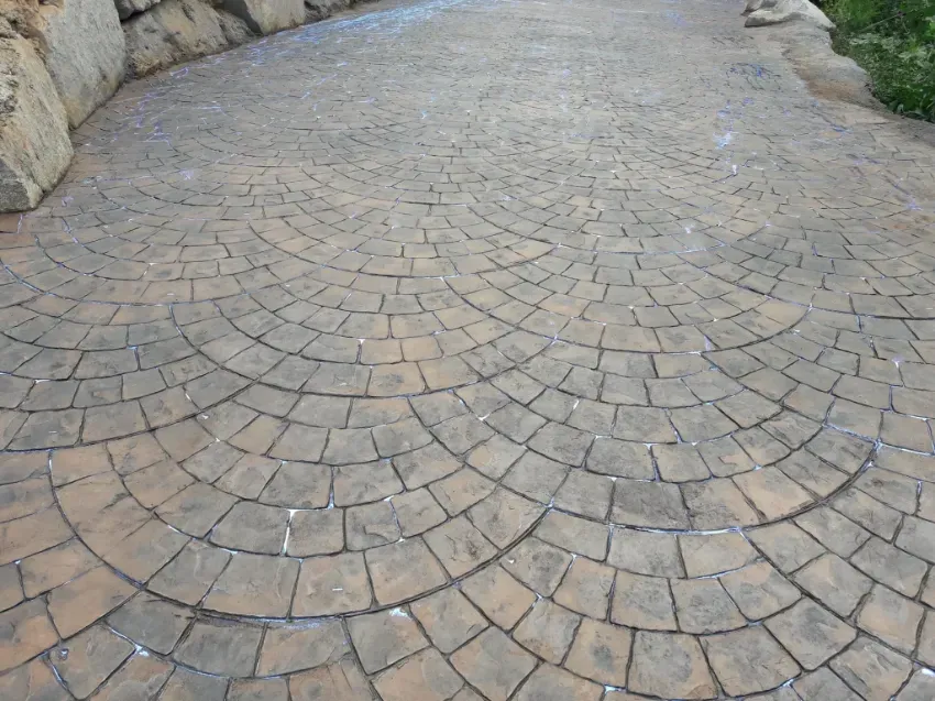 Entrada curva de adoquines con losas de color beige y bordes de piedra.