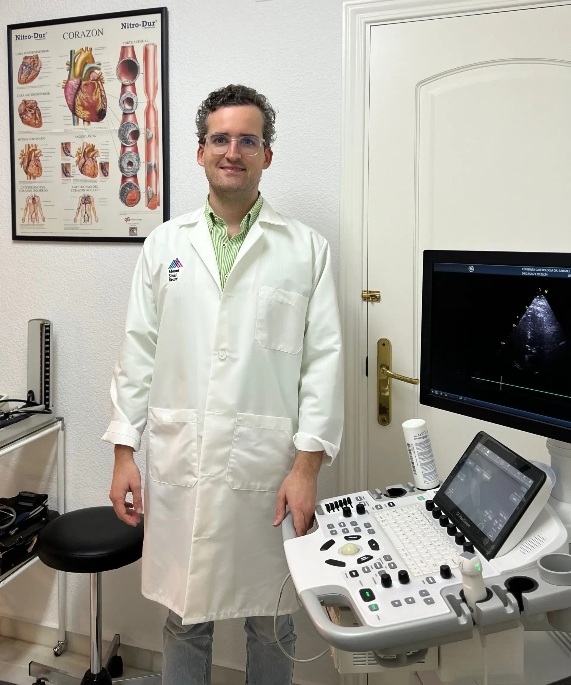 Un hombre con bata de laboratorio está parado frente a una máquina de ultrasonido.