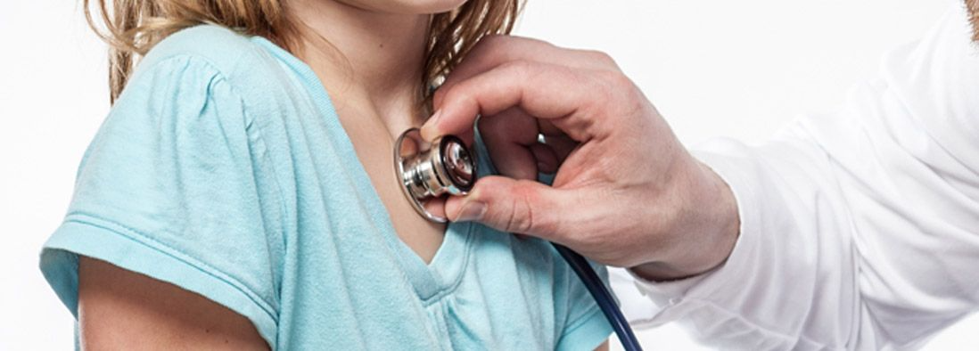 Un médico está escuchando el corazón de una niña con un estetoscopio.