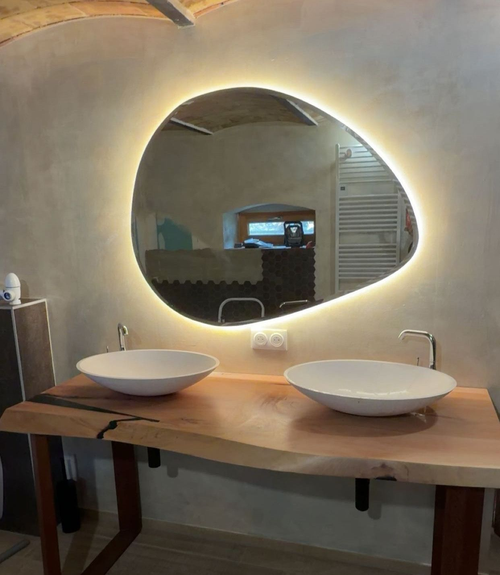 Meuble-lavabo rustique avec deux vasques à poser blanches, un plan de travail en bois et un miroir ovale rétroéclairé
