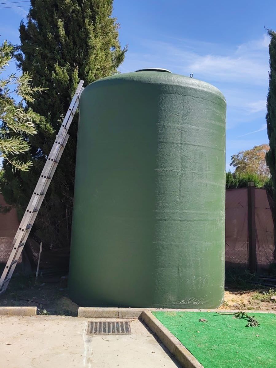Un gran tanque de agua verde con una escalera apoyada en él.