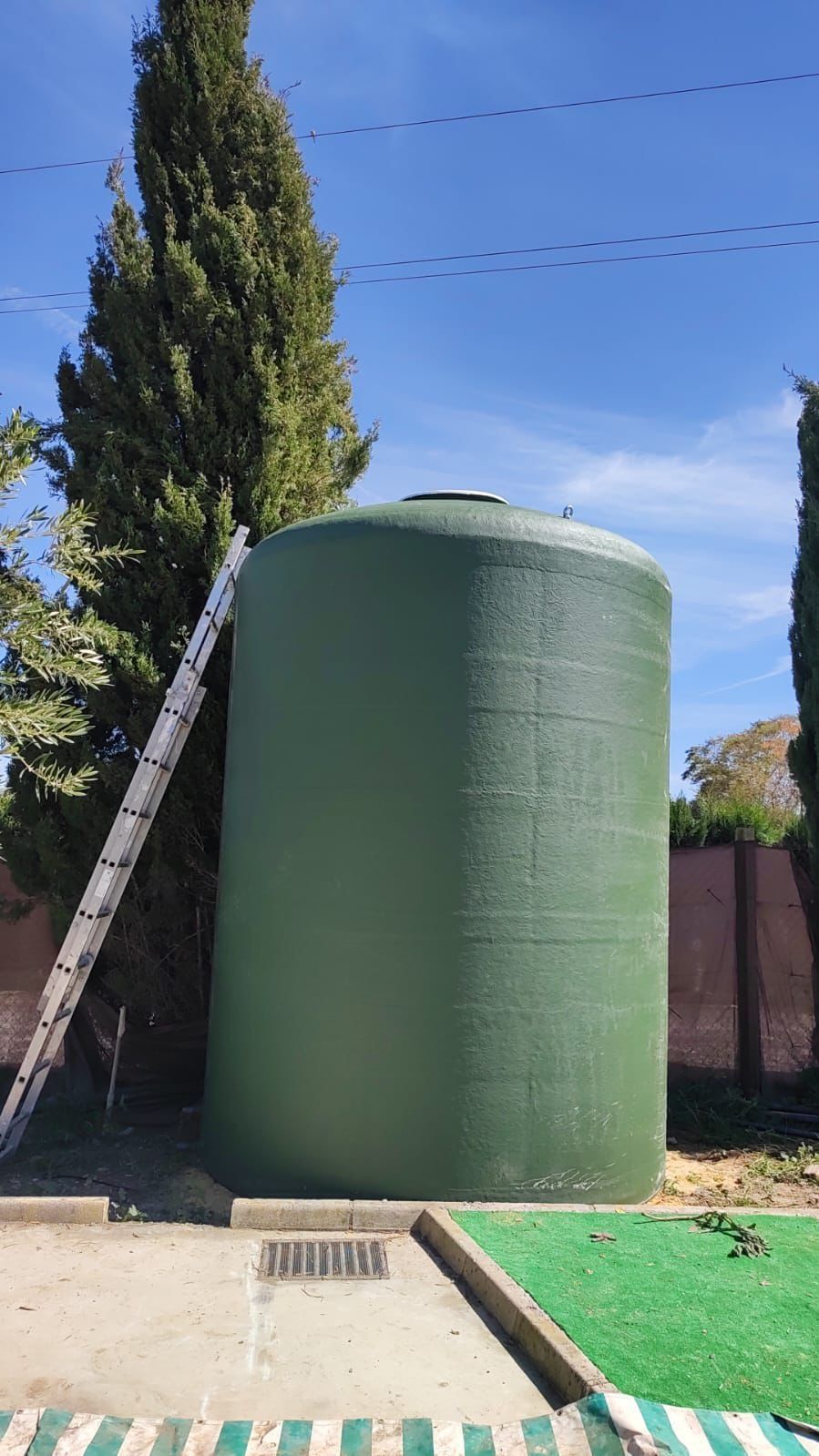 Un gran tanque de agua verde con una escalera apoyada en él.