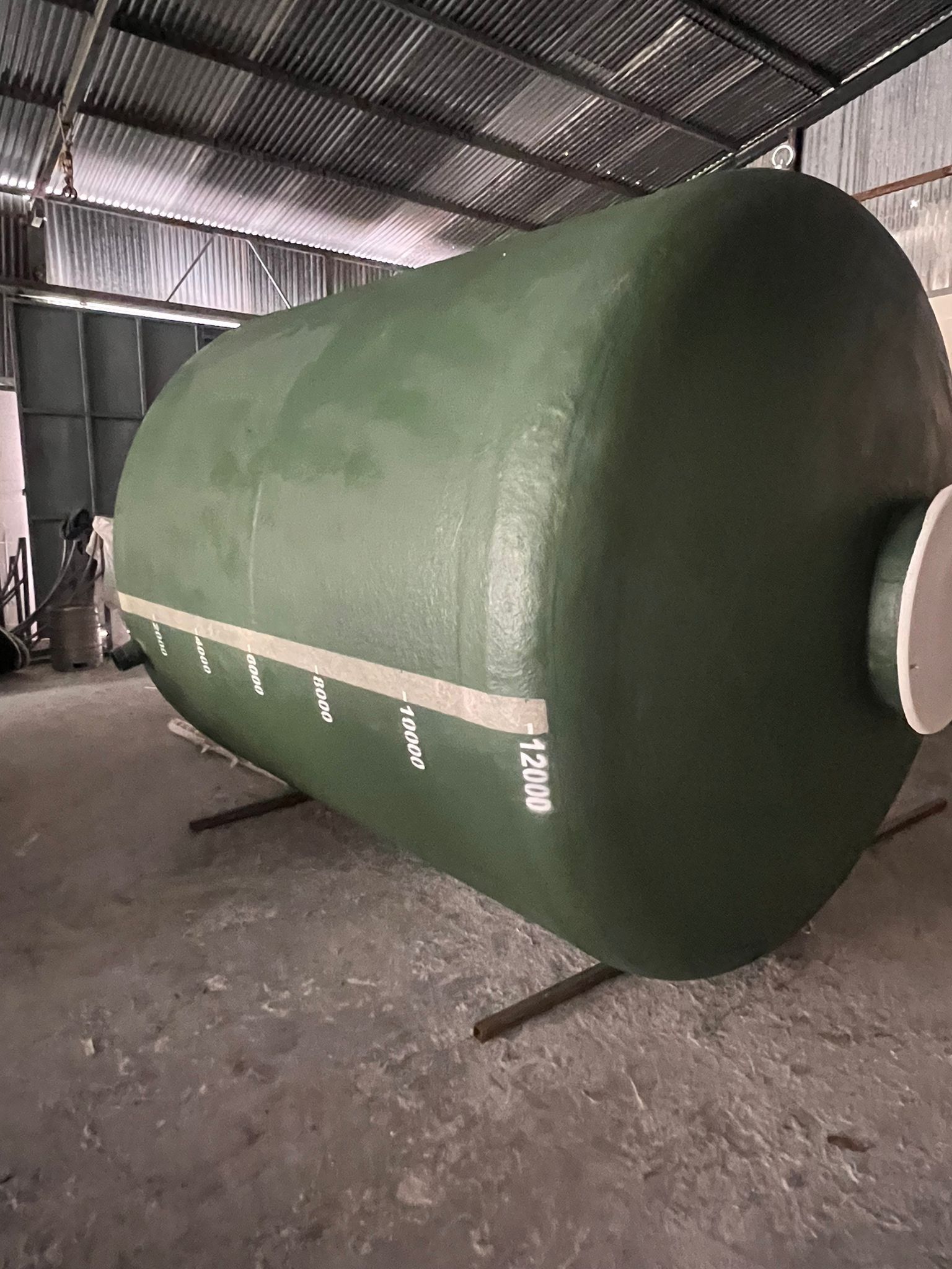 Un gran tanque verde está en un almacén.