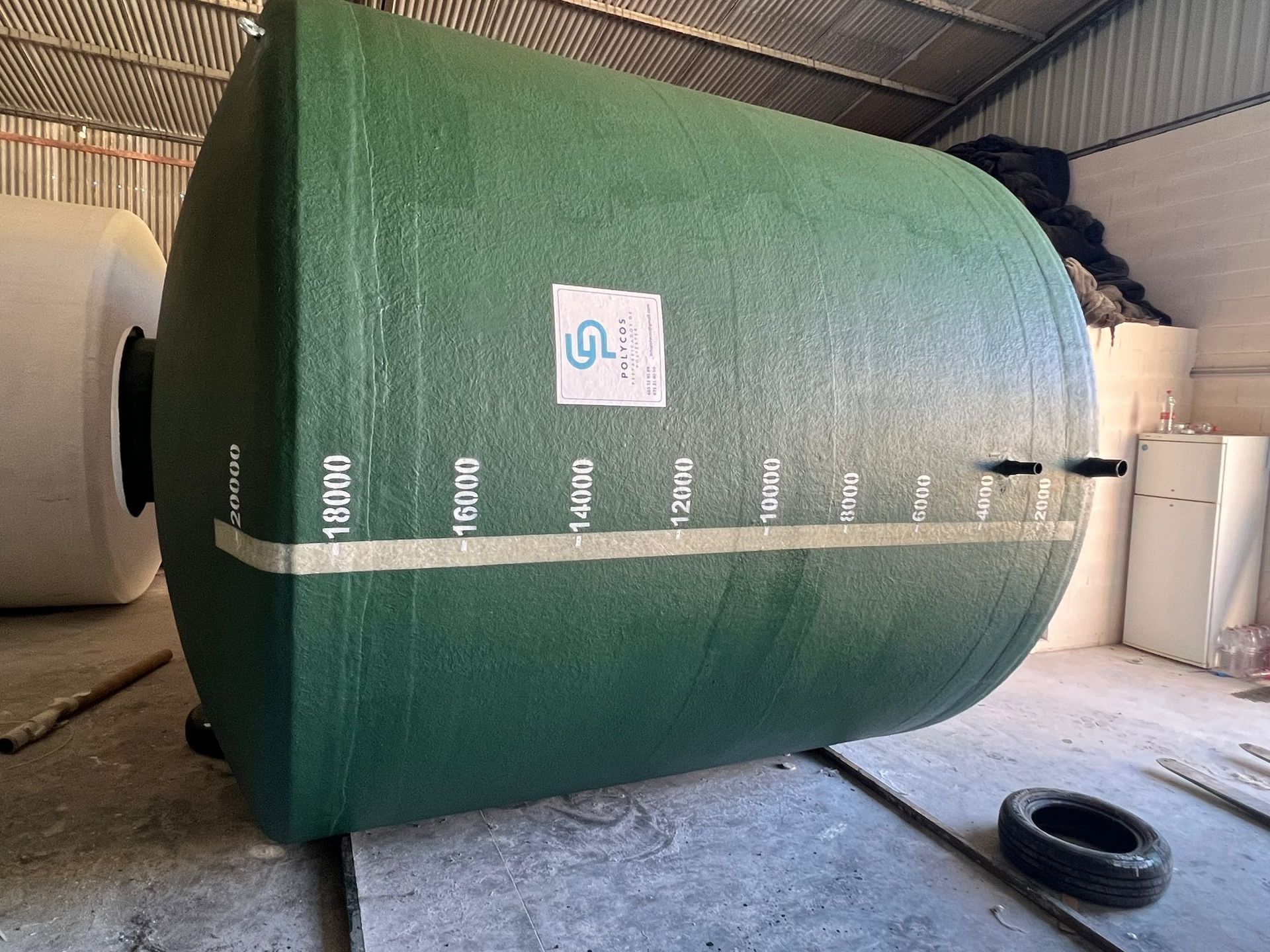 Un gran tanque verde está sentado encima de una mesa de madera en un almacén.