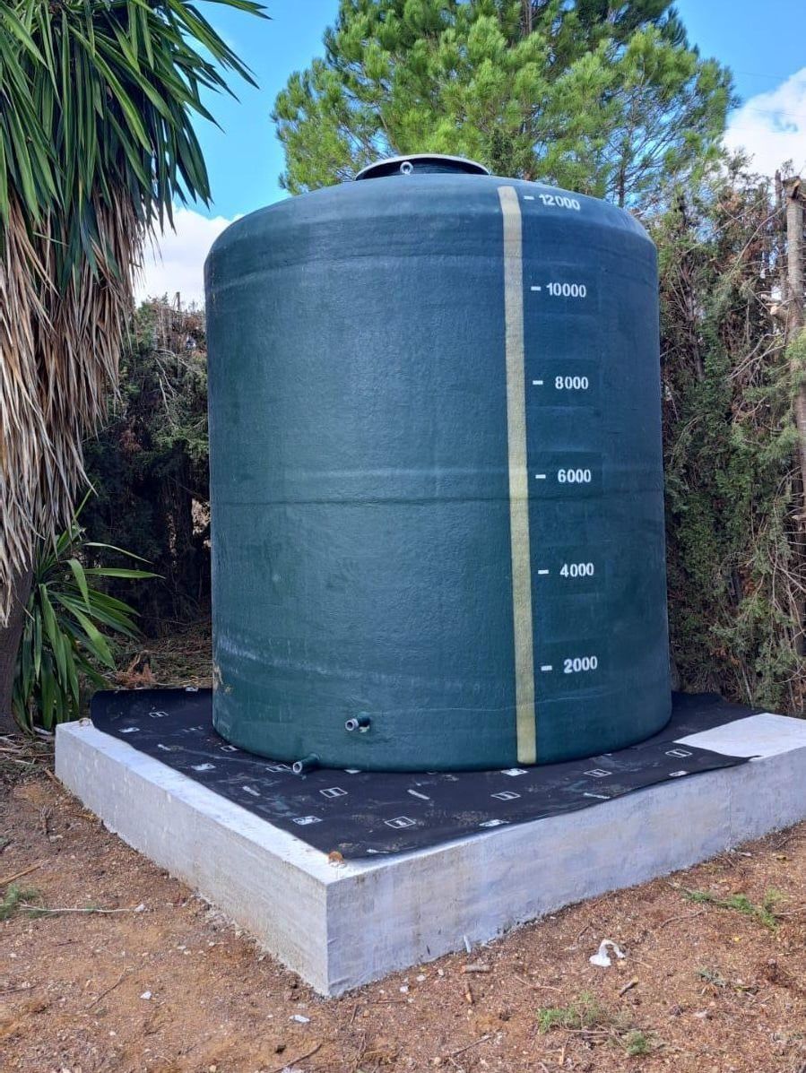 Un gran tanque de agua verde está ubicado encima de una base de concreto.