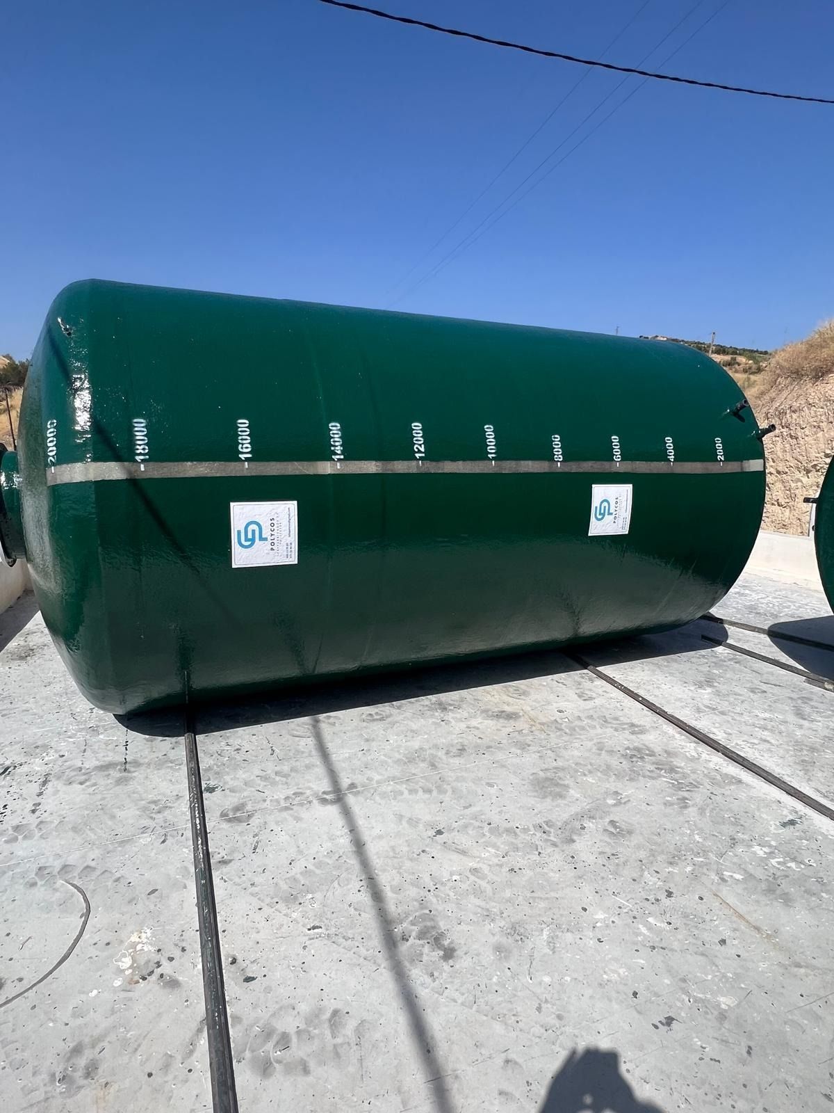 Un gran tanque verde está sentado sobre una superficie de concreto.